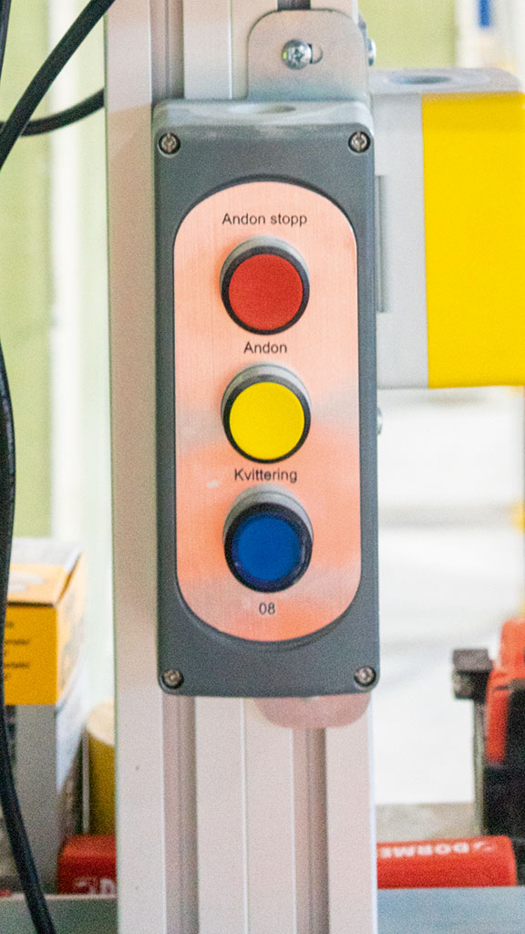 Det finns tre knappar vid varje station. Blått för klart, gult för hjälp eller rött för att stoppa hela produktionslinan. Men hittills har ingen behövt trycka på den röda knappen. Foto: Charlotta von Schultz